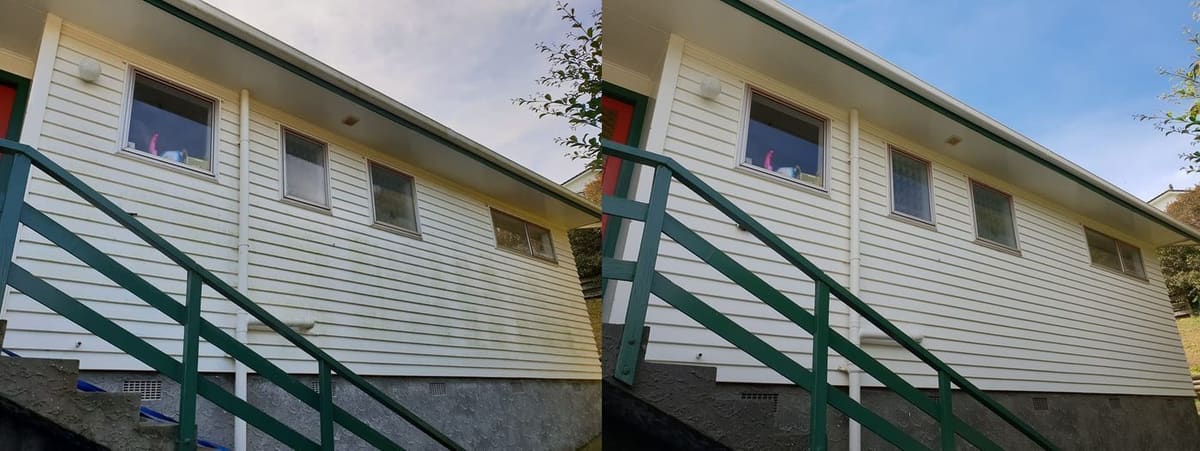 House washing in Newlands, side of a weatherboard house with a green wooden stair rail, green algae streaks before, clean cream weatherboard after