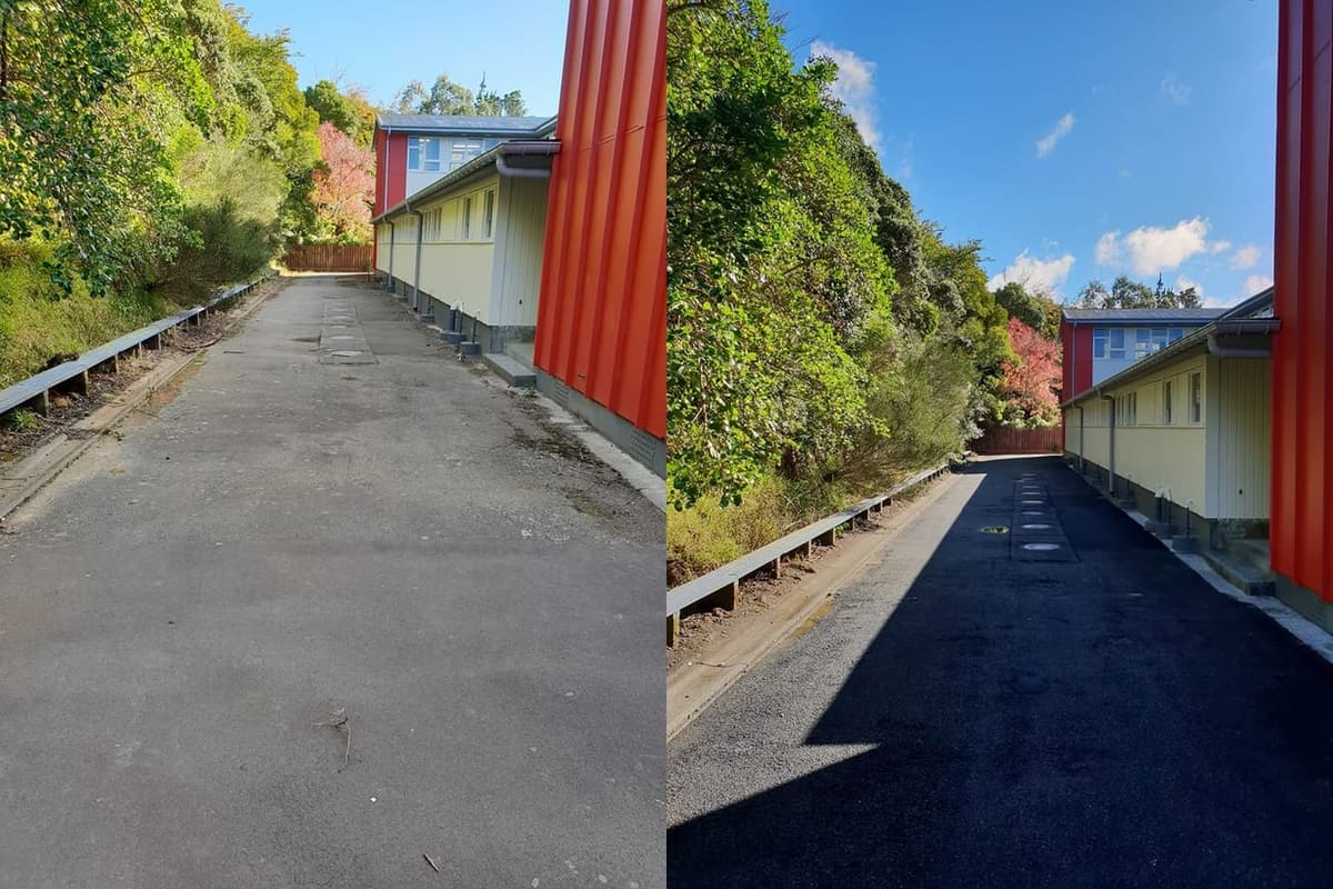 Wellington school path cleaning at Newlands College, asphalt service driveway beside a bright red classroom block softwashed and biocide treated, returning a clean even pavement under autumn light.