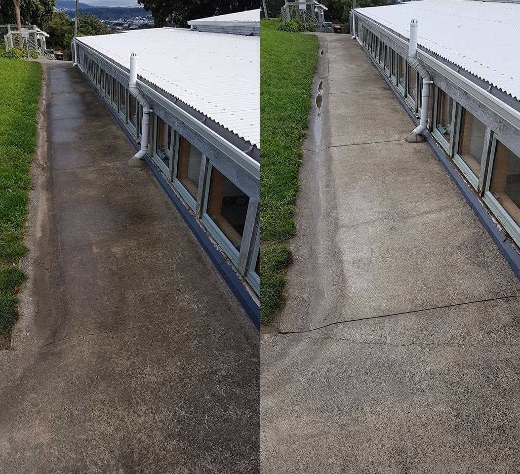 Wellington school path cleaning at Worser Bay School, long concrete corridor alongside classroom block stripped of moss film with biocide treatment, leaving an even pale finish from end to end.